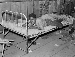 Russell Lee, Boy resting on bed in attic of sharecropper shack. New Madrid County, Missouri, 1938
