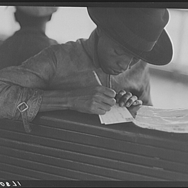 Migratory worker on the Norfolk-Cape Charles Ferry, writing a postcard home to his parents